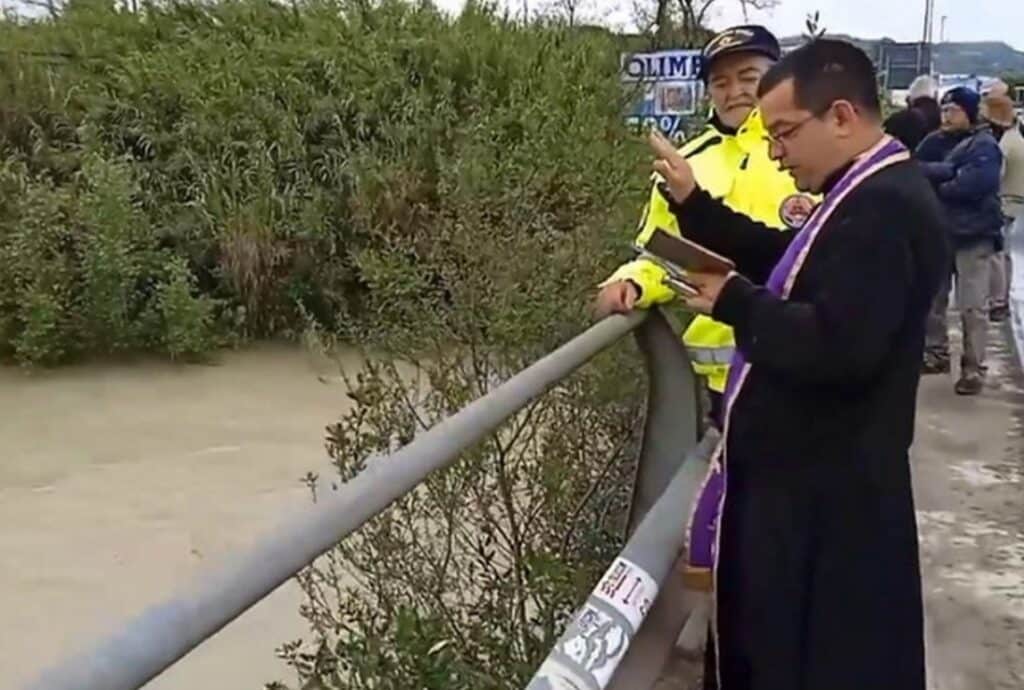 Il parroco benedice il fiume in piena: la foto è virale