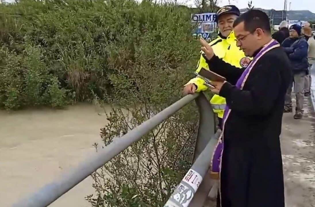 Il parroco benedice il fiume in piena: la foto è virale